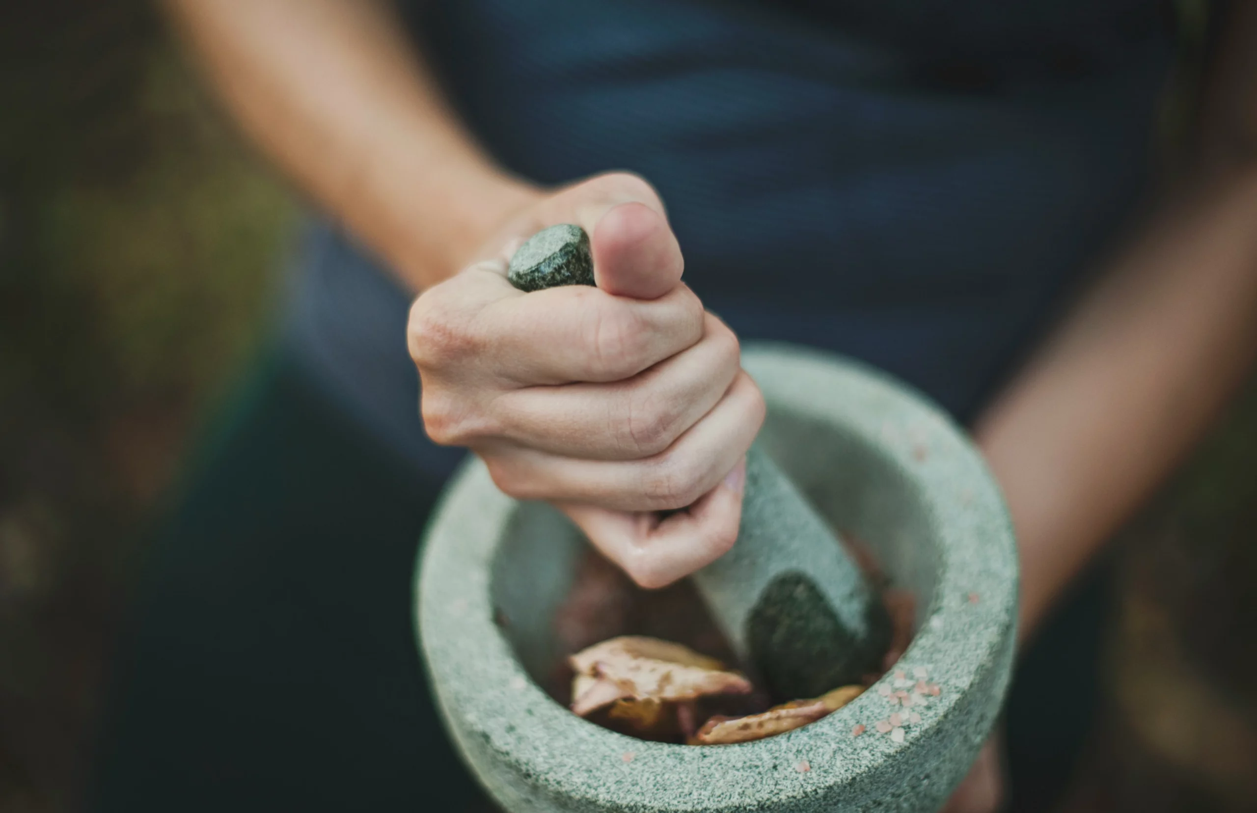 personne qui écrase des herbes dans un mortier